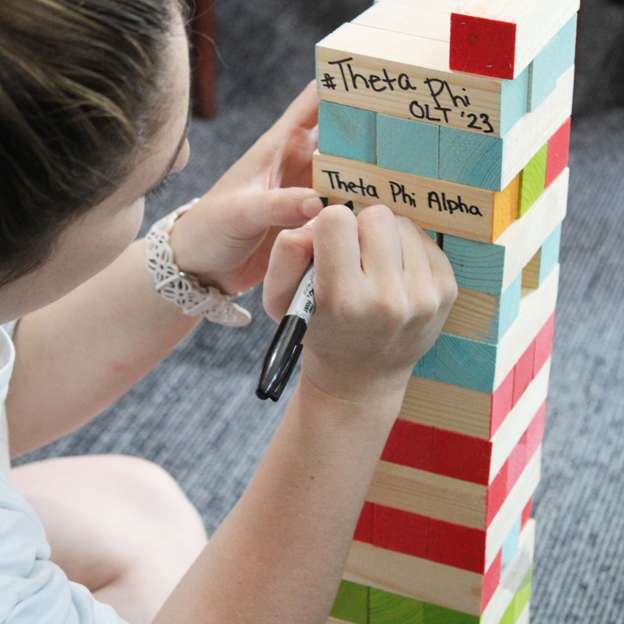 member writing on jenga blocks