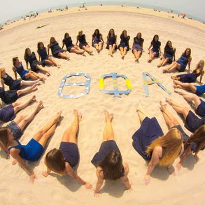 members in a circle around letters at the beach square