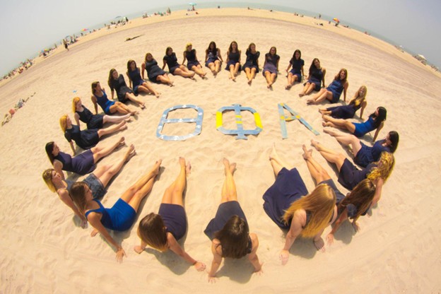 members in a circle around letters at the beach