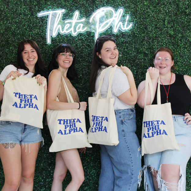 Correct names, members in front of Theta Phi sign holding bags